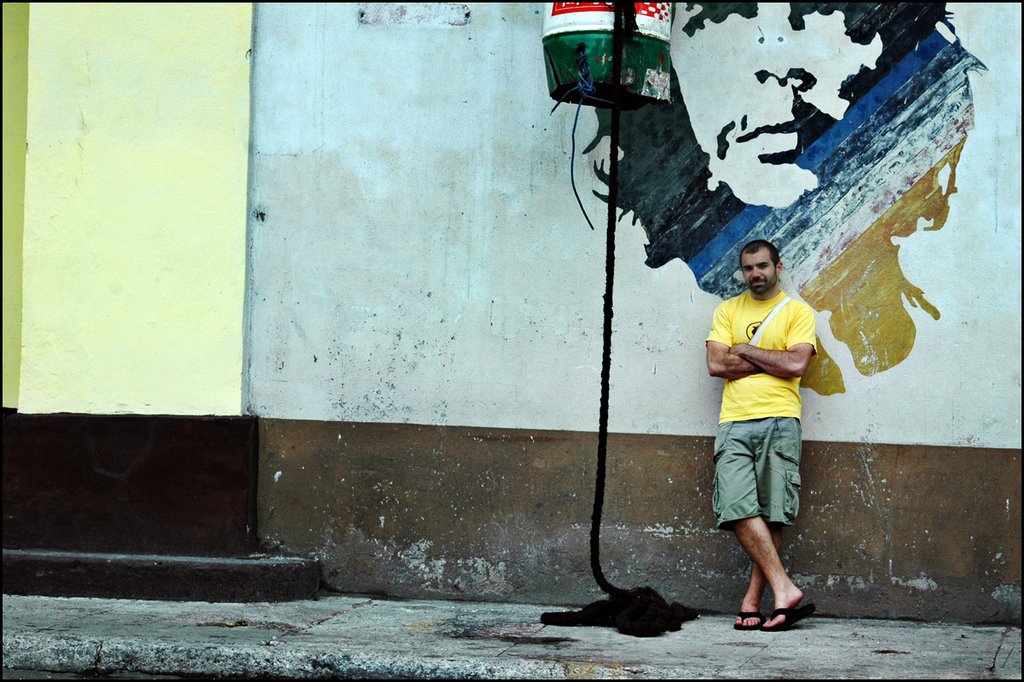 Dave, arms crossed, leaning against a Havana wall beneath a painted mural of Che Guevara